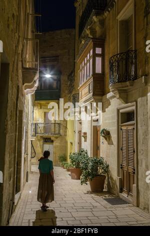 Narrow street with enclosed balcony at night in the fortified city of Birgu aka Vittoriosa, Malta Stock Photo