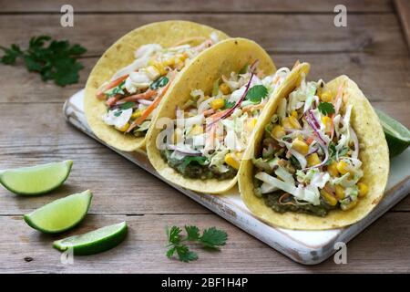 Vegetarian tacos stuffed with cabbage salad on a wooden background. Rustic style. Stock Photo