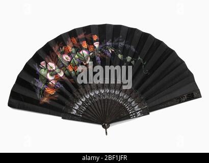 Pleated fan. Pleated fan. Black silk leaf painted with a design of flowers on the obverse. Sticks have a flower and trellis design carved à jour. Stock Photo