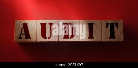 AUDIT word written on wooden blocks on red background. Financial business accounting concept Stock Photo