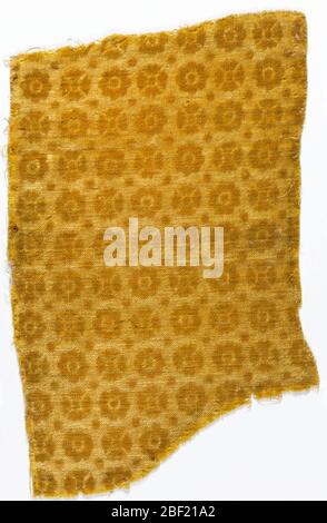 Textile. Close-set repeat of small stylized rosettes alternating with dots, in gold-colored wool velvet. Motifs in relief on pressed ground of same. Stock Photo