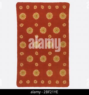 Mosen. Rectangular rug made of wool which is felted, then patterned with tied resist dyeing, leaving large and small dots of yellow in a deep red-orange ground. Touches of green applied by brush. A mosen is a type of rug used in Japanese tea ceremonies. Stock Photo