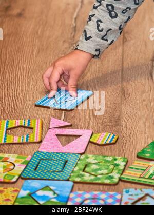 Kid's hands with Montesori pazzls close-up. Montesori wooden game for the development of children. Child development retardation. Stock Photo