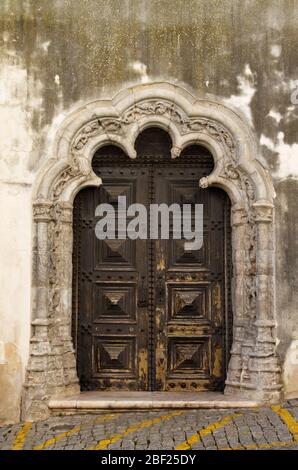 The lateral entrance of Elvas main church, Nossa Senhora da Assuncao, and former Se Cathedral. Wood carved door framed by rich stone carving work in M Stock Photo