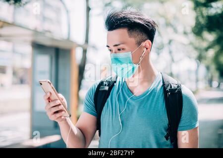 young man wear mask and walking on street using mobile phone Stock Photo