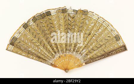 Pleated fan. Pleated fan with a fine silk net leaf appliquéd with gold-colored metal foil and sequins in chevron pattern; reverse: plain. Celluloid sticks inlaid with sequins. Celluloid guards with copper and inlaid with gold-colored metal foil. Stock Photo