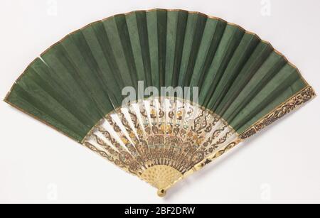 Pleated fan and case. Pleated fan. Green silk weave leaf finished with narrow gilt paper at top. Pierced and carved ivory sticks with details painted or overlaid with gold foil. Stock Photo