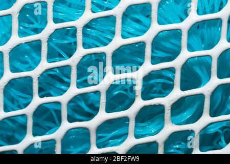 Metal enameled grid. abstract background. blue cloth behind the metallic grate. iron white mesh Stock Photo