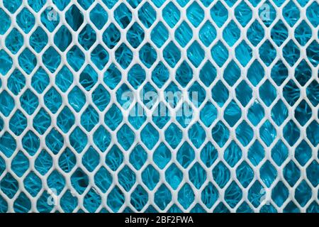 Metal enameled grid. abstract background. blue cloth behind the metallic grate. iron white mesh Stock Photo