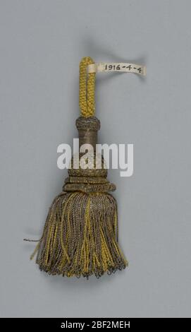 Tassel. Tassel with a turned wooden core (cylinder, bulb and flange) covered with yellow silk and gilt threads in wrapping, trellis, and twisted rolls. Skirt of twisted yellow silk and gold threads. Loop of yellow silk cord at top. Stock Photo