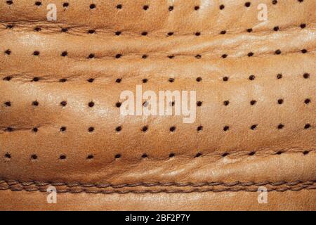 Brown leather texture with holes and stitches. creased material with seams macro background Stock Photo
