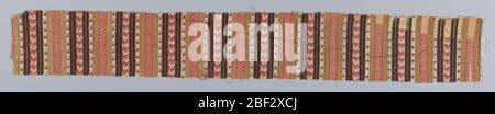Fragment. Fragment printed in red, brown and black on a white ground in a design of solid vertical stripes alternating with stripes of geometric patterning. Stock Photo
