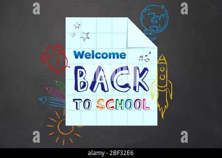 Paper sheet with text WELCOME BACK TO SCHOOL and drawings on blackboard Stock Photo