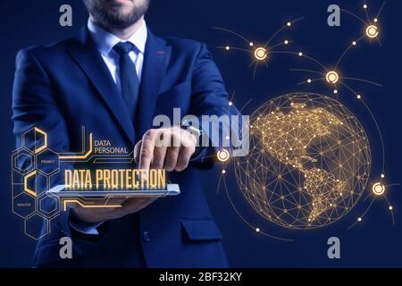 Businessman with tablet computer and hologram projection of data protection service on dark background, closeup Stock Photo