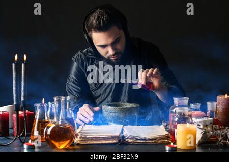 Male alchemist making potion on dark background Stock Photo