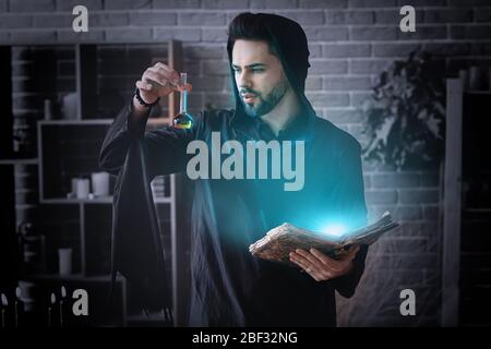 Male alchemist with spell book and elixir in laboratory Stock Photo