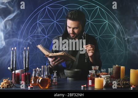 Male alchemist making potion on dark background Stock Photo