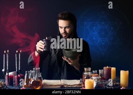Male alchemist making potion on dark background Stock Photo