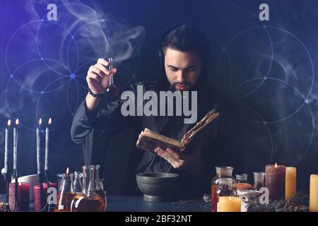 Male alchemist making potion on dark background Stock Photo
