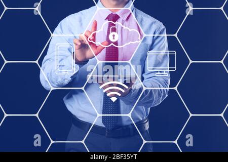 Businessman with tablet computer using cloud storage service on dark background Stock Photo