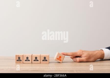 Man removing wooden cube with drawn worker from table. Concept of dismissal Stock Photo
