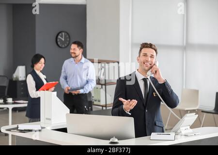 Male receptionist talking on phone in office Stock Photo