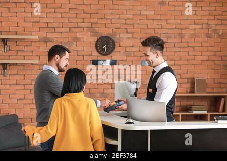 Couple paying for hotel room at reception Stock Photo