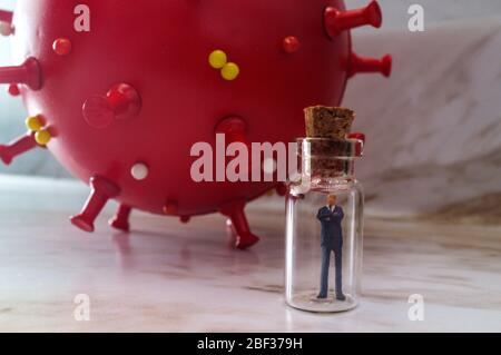 Miniature businessman practicing social distancing by quarantining in glass bottles to slow the spread of the deadly coronavirus metaphor Stock Photo