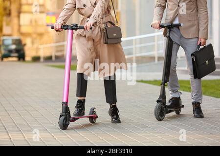 Young couple with kick scooters on city street Stock Photo