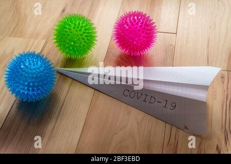 Deadly epidemic coronavirus with paper airplane that reads COVID-19 as metaphor for closed airports Stock Photo