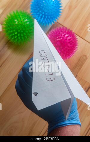 Deadly epidemic coronavirus with paper airplane that reads COVID-19 as metaphor for closed airports Stock Photo