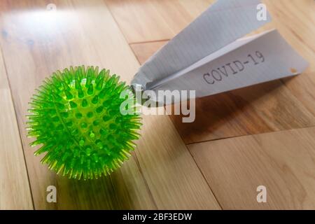 Deadly epidemic coronavirus with paper airplane that reads COVID-19 as metaphor for closed airports Stock Photo