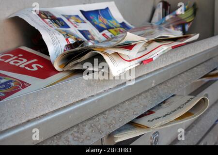 UNWANTED AND UNREAD JUNK MAIL OVERFLOWING FROM THE LETTERBOXES OF AN APARTMENT BLOCK IN SYDNEY, NEW SOUTH WALES, AUSTRALIA. Stock Photo