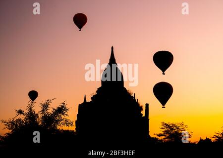 Hot air balloons at sunrise behind and unnamed pagoda in Bagan, Myanmar