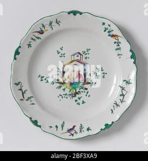 Plate. Circular cavetto, scalloped rim irregularly ten-sided. Chinoiserie decoration: seated man and boy holding parasol under double-roofed shelter supporting a bell and a bird, the whole surrounded by foliage. Border of alternating birds and green latticed panels. Stock Photo