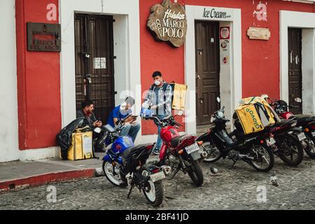 Delivery man waiting. Restaurants are closed and only deliveries are allowed during coronavirus COVID pandemic, Antigua Guatemala curfew Stock Photo