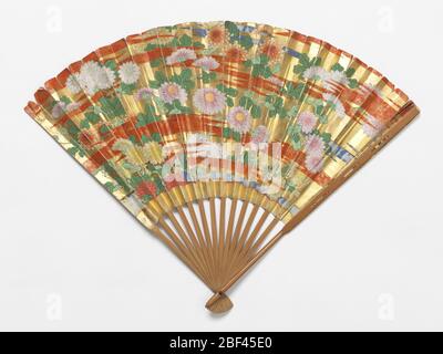 Pleated fan and case. Pleated fan. Painted paper leaf showing flowers and red clouds against a gold background. Bamboo sticks. Stock Photo