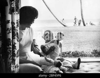 First Lady of the United States JACQUELINE KENNEDY daughter CAROLINE KENNEDY. President John F. KENNEDY can be seen in the distance on the beach. Stock Photo