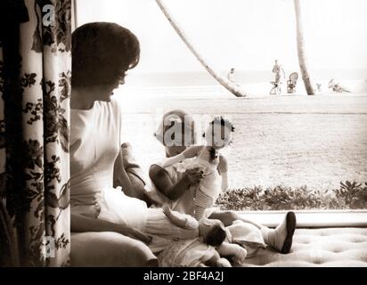 First Lady of the United States JACQUELINE KENNEDY daughter CAROLINE KENNEDY. President John F. KENNEDY can be seen in the distance on the beach. Stock Photo