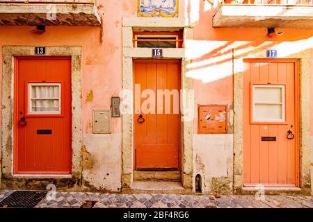 Three painted orange doors in a coral building in the Alfama district of Lisbon Portugal Stock Photo