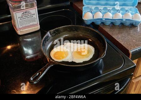 Breakfast Two sunny side up eggs frying in cast iron skillet Stock Photo