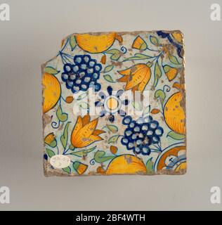 Four tile. Two tiles each of a similar design, in blue, green and neutral yellow, with fleurs-de-lis at four corners, leaves and two small bunches of grapes; in center of tiles a and b, a pomegranate, of tiles c and d, a large bunch of grapes. Stock Photo