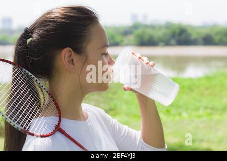 A badminton drinking water during practice at the park on a hot day. Stock Photo