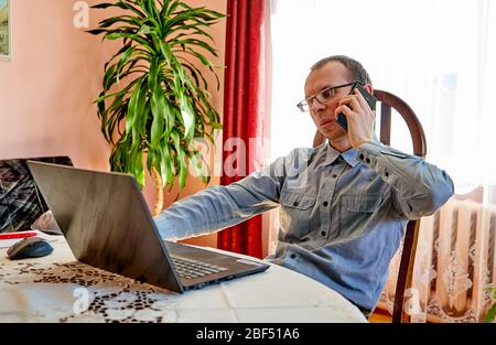 Man talking with phone while working from home office. Stock Photo