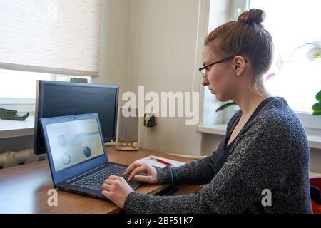Young woman working on laptop at home during isolation time Stock Photo