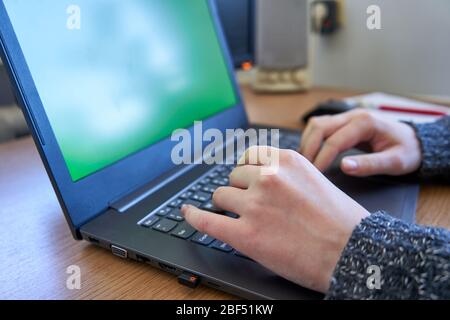 Woman typing on laptop with green screen. Stock Photo