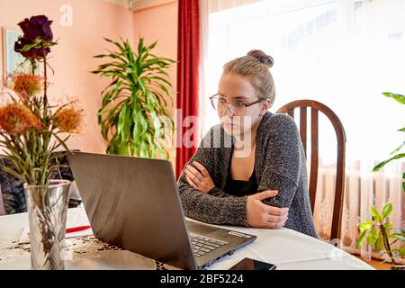 Mature woman working on laptop. Looking at screen and thinking what to do next. Stock Photo
