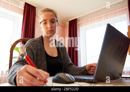 Woman working with laptop and writing something down. Home office. Stock Photo