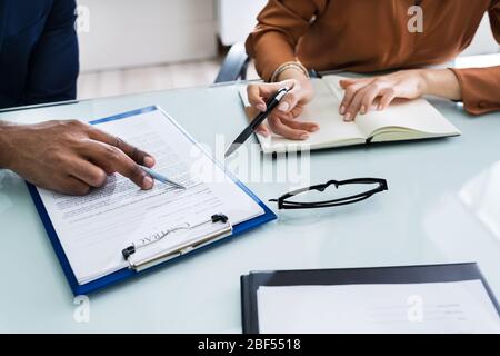 Two Businesspeople Hand Analyzing Document Over Glass Desk Stock Photo