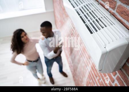 Portrait Of Happy Couple Holding Remote Control Air Conditioner Stock Photo